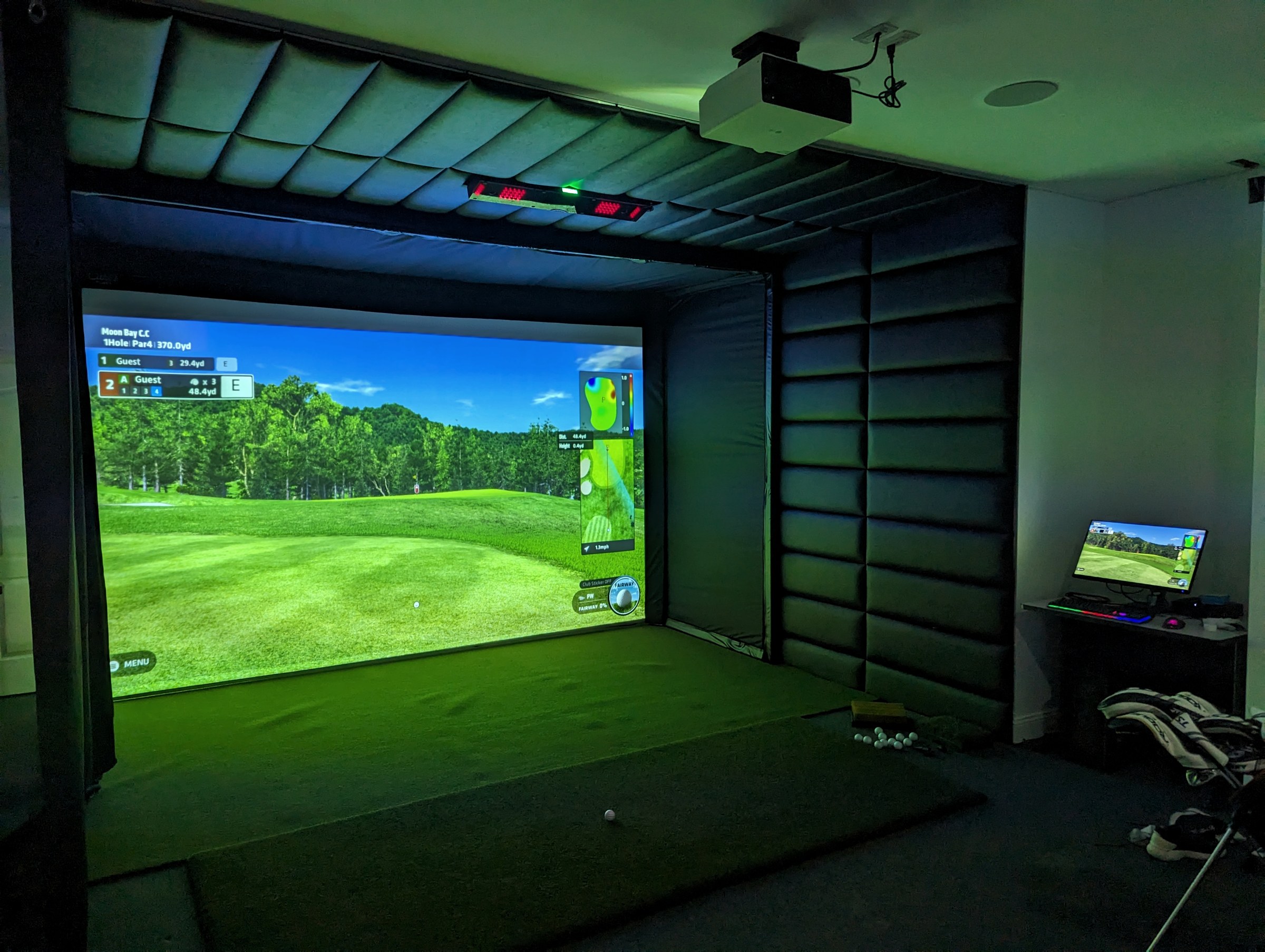Golf simulator installation with projector, padded bay, and control station